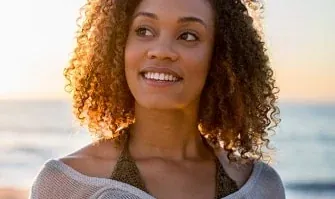 A smiling woman, from the practice's own page on metal-free fillings.